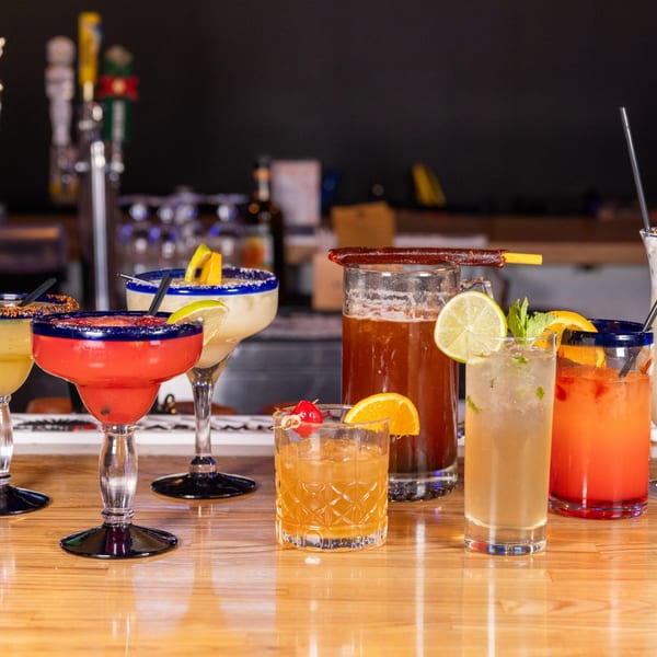 Assortment of colorful Mexican cocktails and margaritas on a wooden bar top at Jefe's Cantina + Cocina.